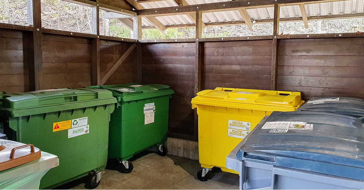 Kerrostalon jätekatos sisältäpäin kuvattuna, erivärisiä 660-litraisia jäteastioita.