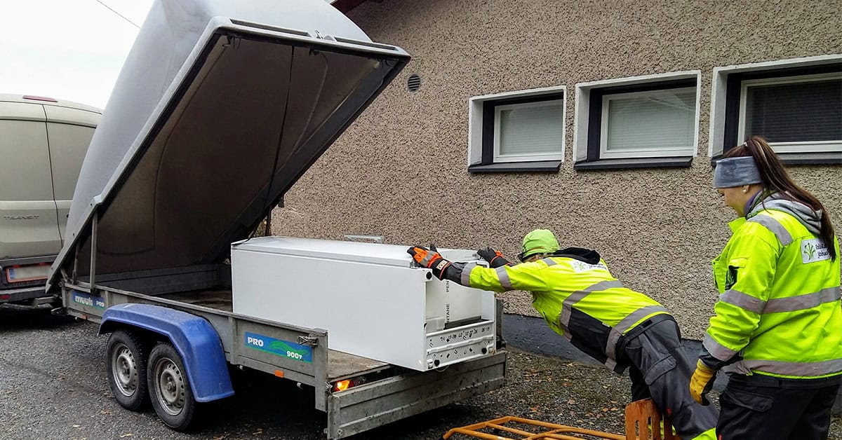 Punatiilinen toimistorakennus, jonka edessä vehreää puustoa ja lipputanko.