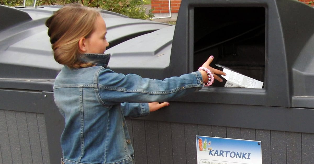 Näkymä omakotitalon pihatielle, vasemmassa laidassa valkoinen jätekatos, jonka räystäässä roikkuu kukka-amppeli.