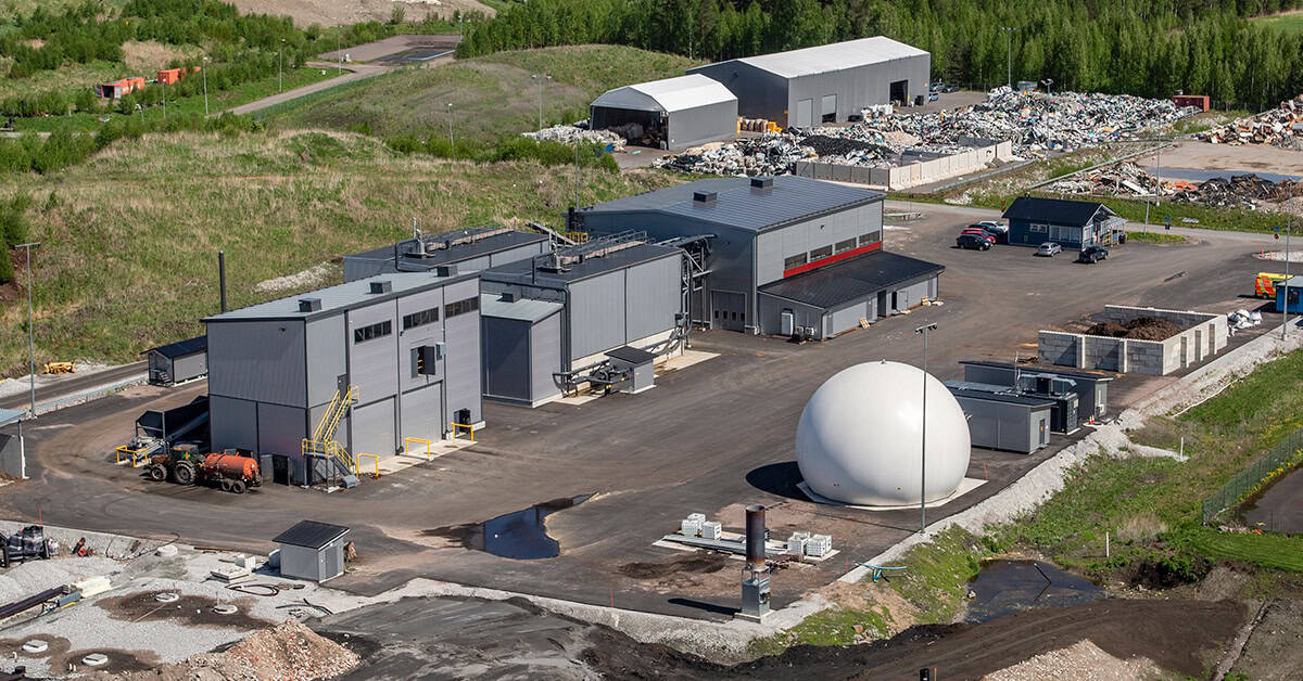 Näkymä omakotitalon pihatielle, vasemmassa laidassa valkoinen jätekatos, jonka räystäässä roikkuu kukka-amppeli.