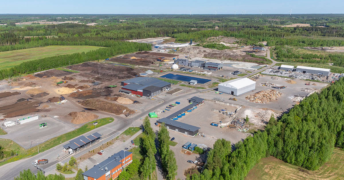 Punatiilinen toimistorakennus, jonka edessä vehreää puustoa ja lipputanko.